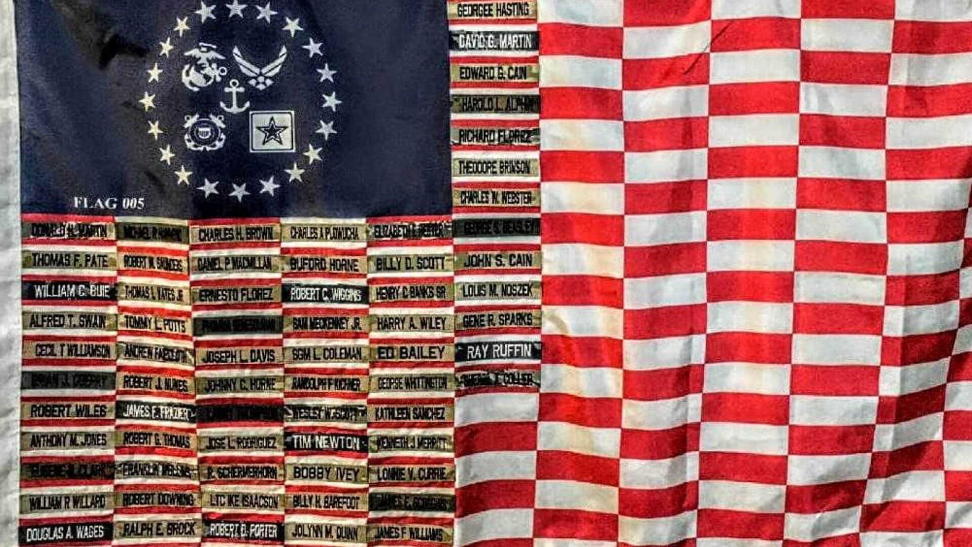 Flag 005 up close: rows of uniform name tapes sewn into the stripes beneath a blue union of service insignia.